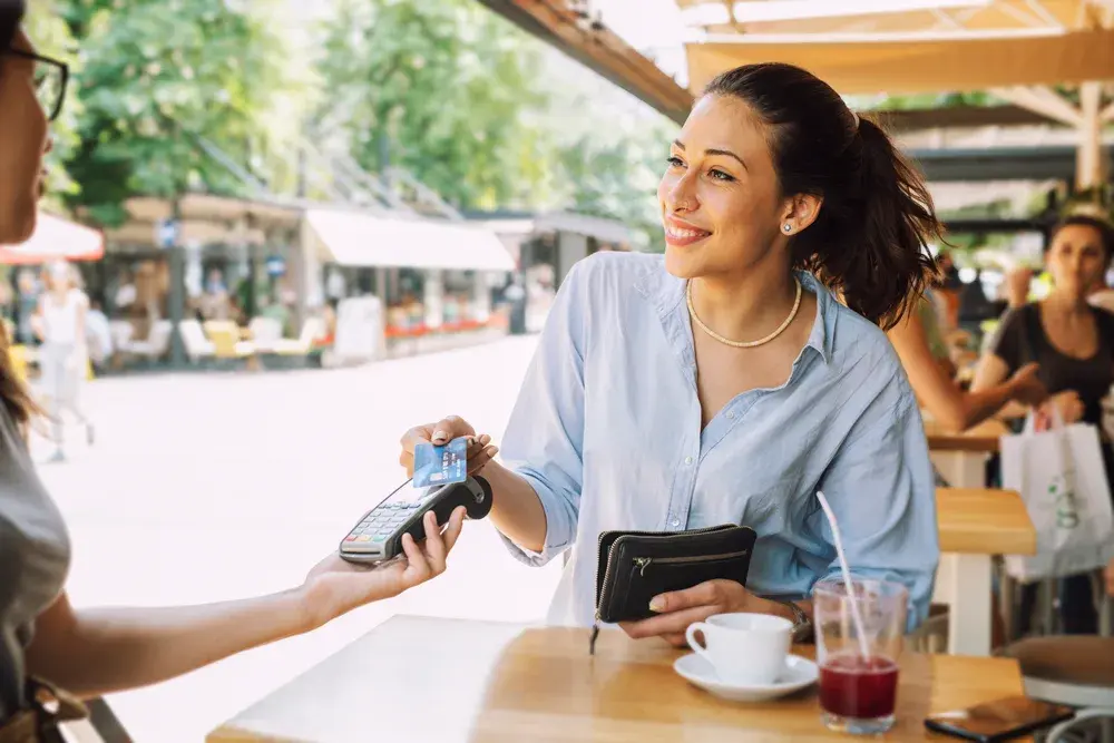 Woman using tap to pay at cafe
